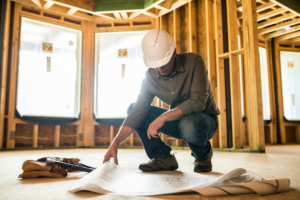 Ckdremodelingmiltonflquestionstoaskageneralcontractorlookingatplansinaframedhome ultimate home remodeling and construction A construction worker reading blueprints